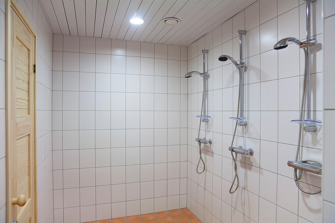 A large shower room, tiled in white tiles, with three showers. Changing room and a wet room.
