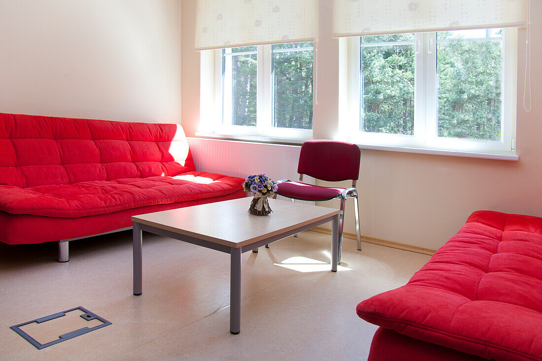 Ein Lehrerzimmer in einer Schule, zwei rote Sofas und ein Tisch. 