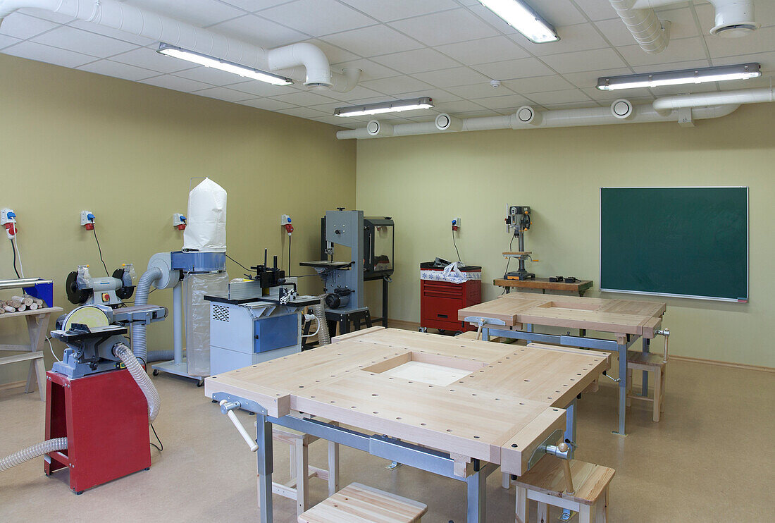 Ein Klassenzimmer für einen technischen oder praktischen Kurs. Holzbearbeitung und Leichtbau. Schraubzwingen, Maschinen und Arbeitsflächen.