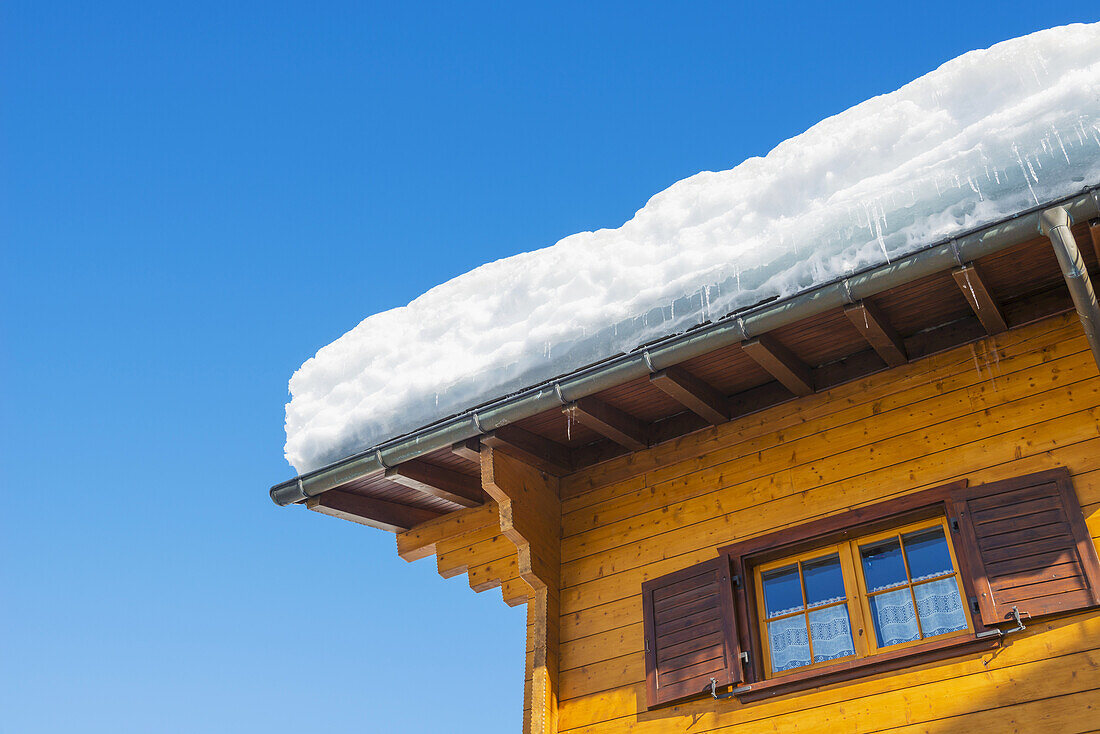 Schnee auf einem Dach vor einem blauen Himmel; San Bernardino, Graubünden, Schweiz