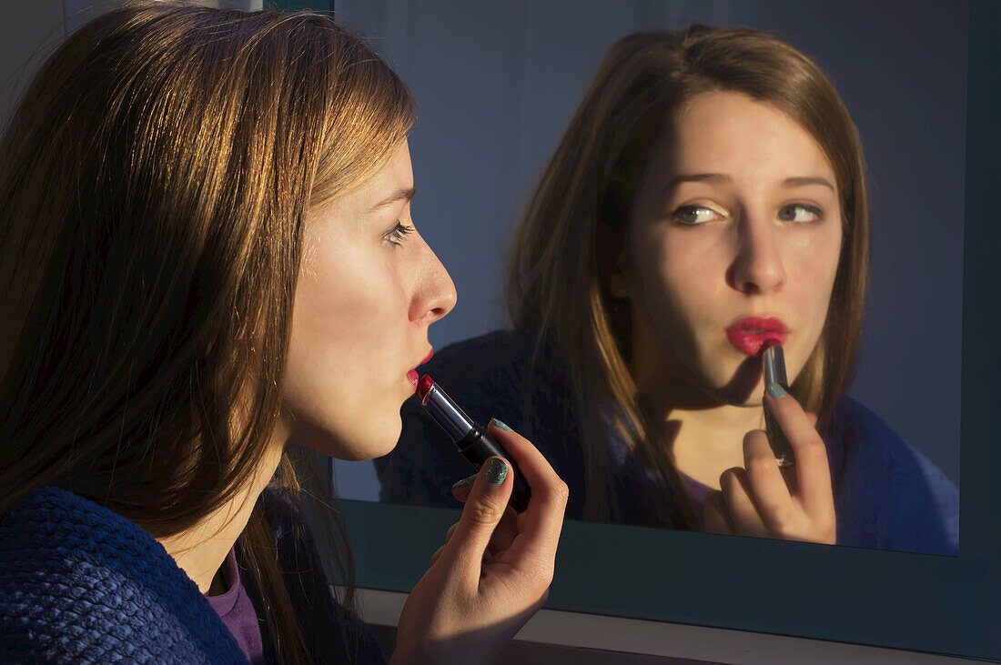 Mädchen im Teenageralter, das sich im Spiegel schminkt; England