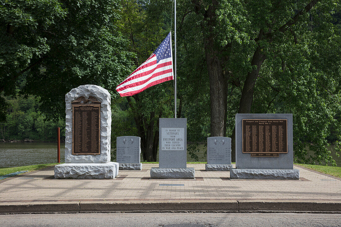 Kriegerdenkmäler, beschriftete Grabsteine und amerikanische Flagge zu Ehren von US-Kriegsveteranen auf einem Friedhof.
