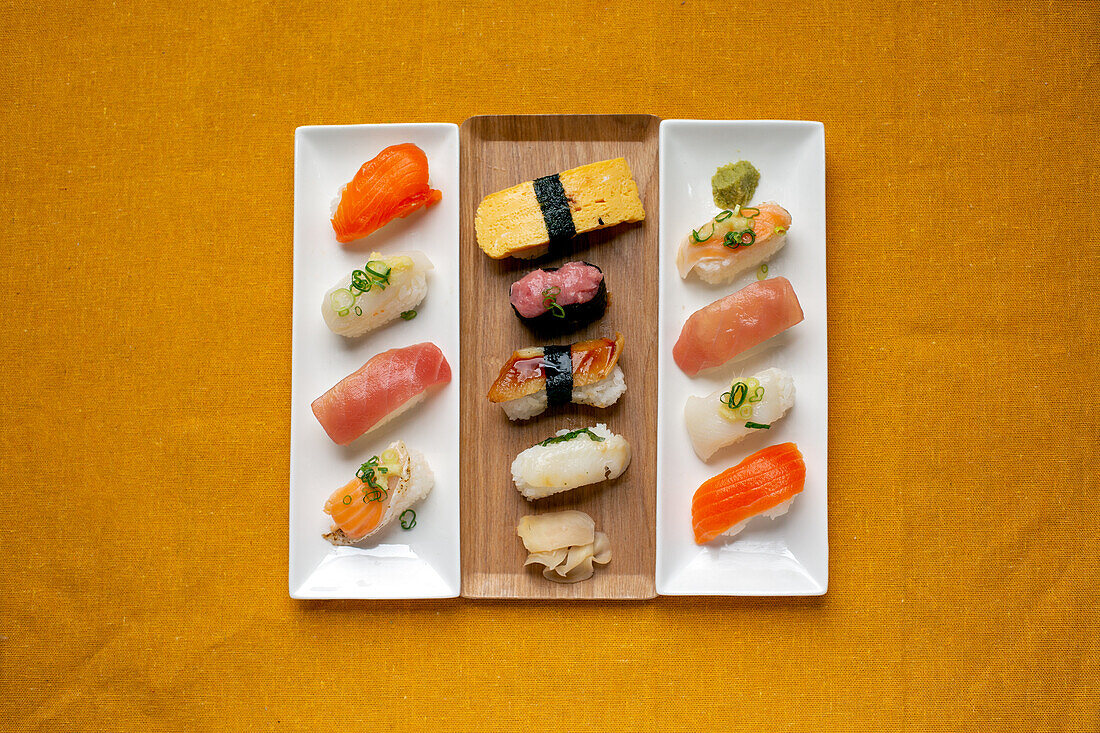 Sushi-Platte, eine Auswahl an rohem Fisch und Reissnacks mit Essstäbchen. 