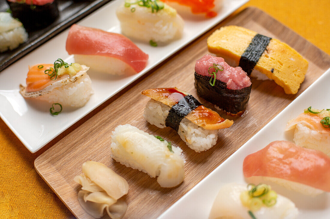 Sushi-Platte, eine Auswahl an rohem Fisch und Reissnacks mit Essstäbchen. 