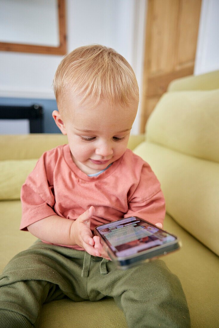 Toddler looking at smart phone indoors
