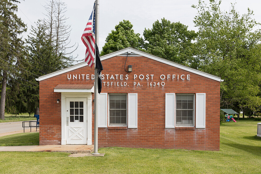 Ländliches US-Postgebäude mit wehender amerikanischer Flagge.