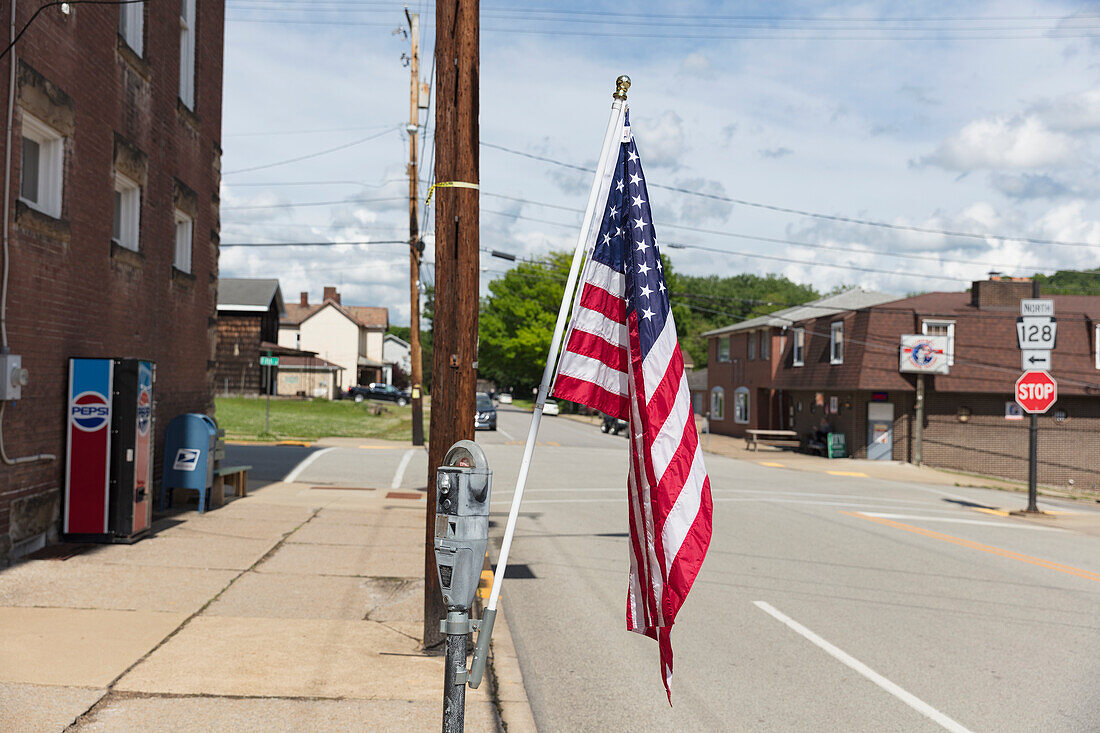 Amerikanische Flagge, die an einem Laternenpfahl auf einer verlassenen Hauptstraße weht.