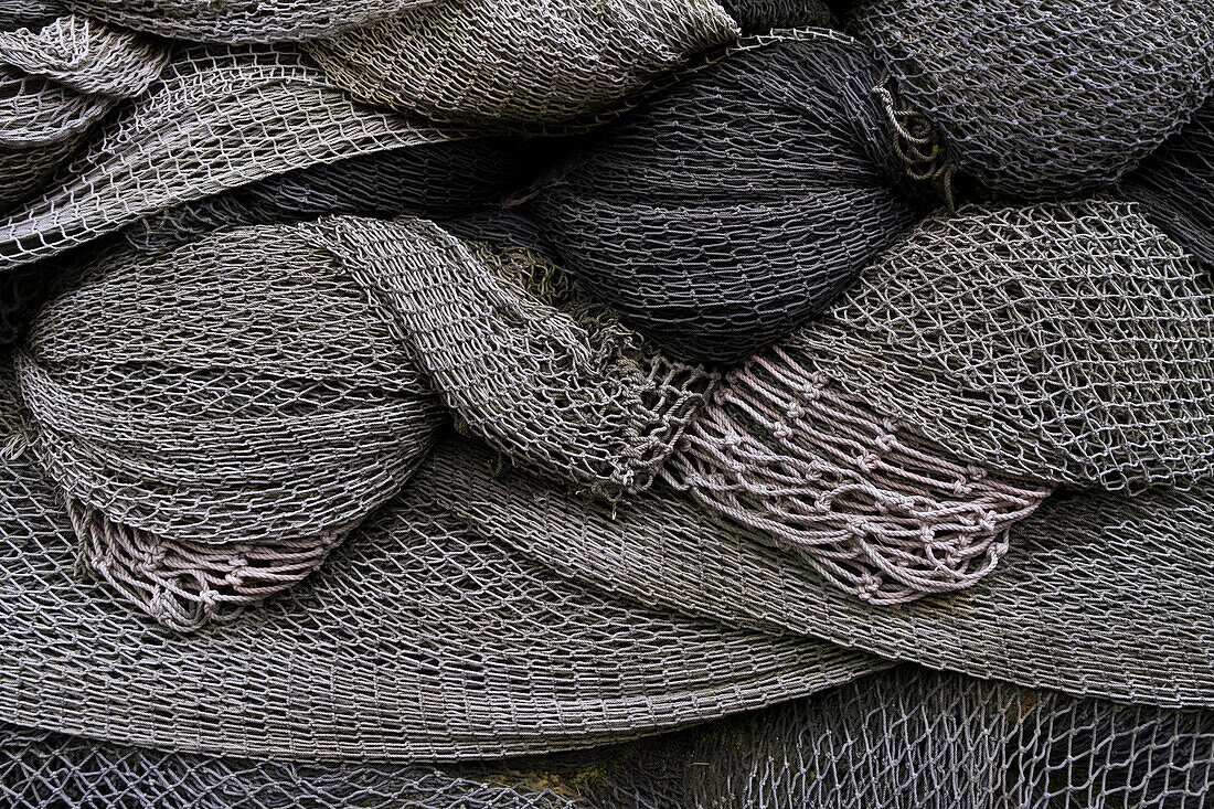 A heap or pile of commercial fishing nets, grey netting folded up. 
