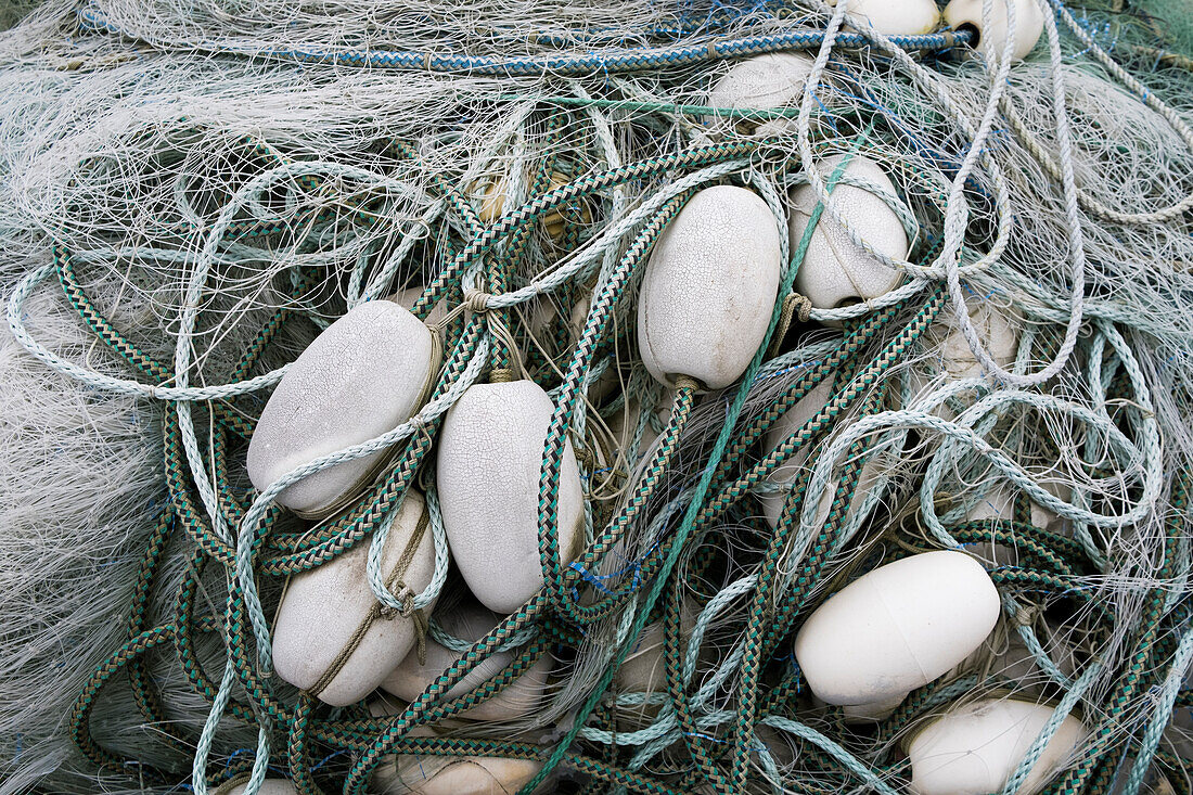 Ein Stapel kommerzieller Fischernetze mit Seilen und Plastikschwimmern. 
