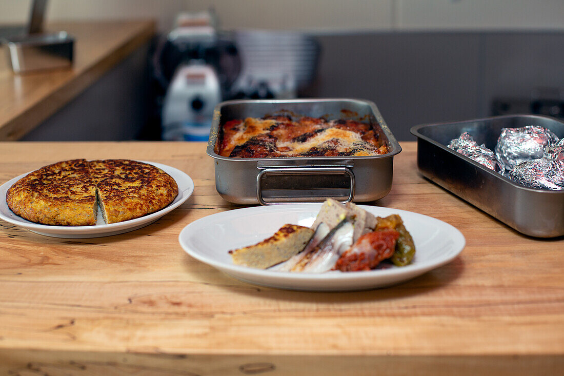 A man preparing food dishes, plates of Italian food on a restaurant kitchen counter. 