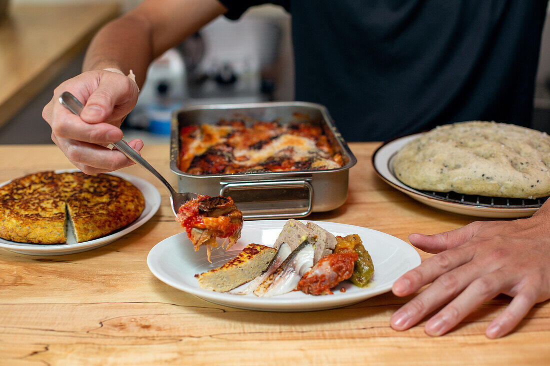 Ein Mann bereitet Gerichte, Teller mit italienischem Essen, auf einer Restauranttheke vor. 