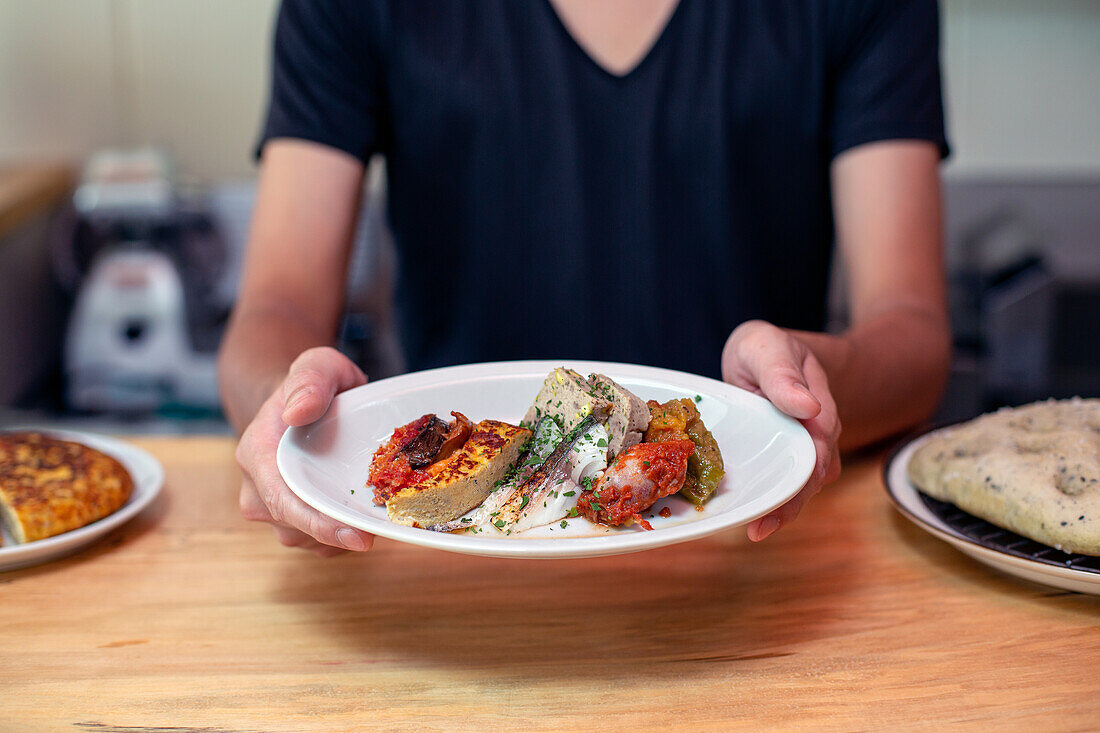 Ein Mann, der an einer Restauranttheke steht und Teller mit gekochten Speisen präsentiert, Menügerichte.