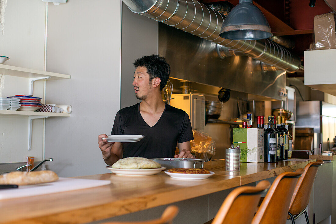 A chef working in a restaurant, at the pass preparing plates of food for service, 