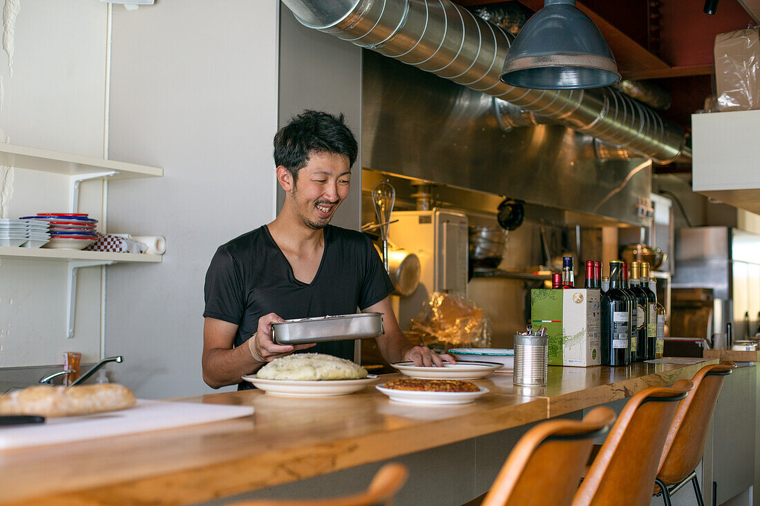 A chef working in a restaurant, at the pass preparing plates of food for service, 