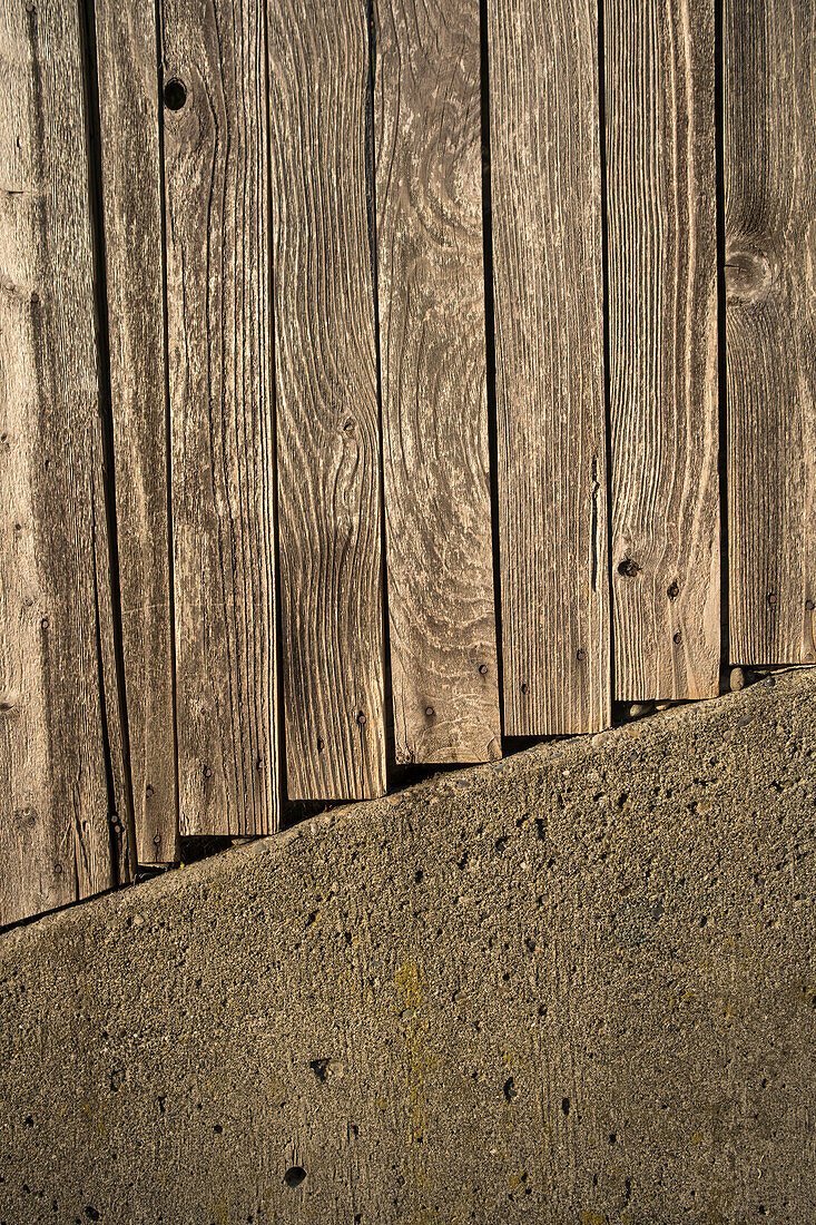 Bretter eines Holzzauns und eine Betonmauer.