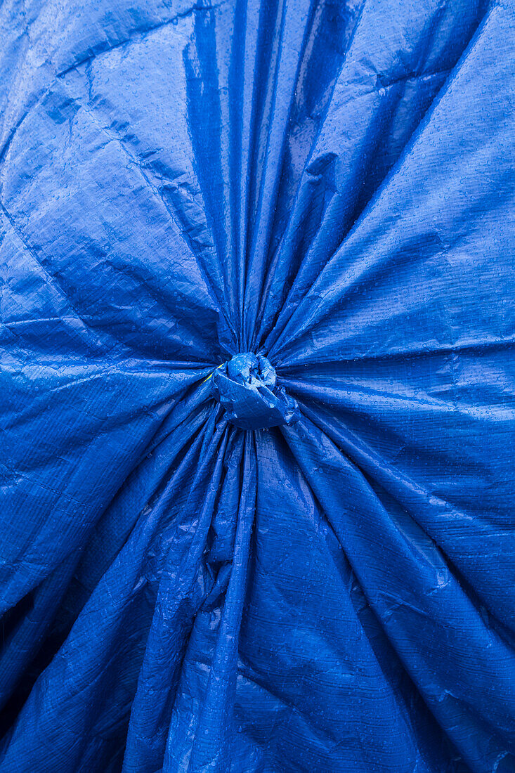 Close up of a tarpaulin cover, knotted with pleated pattern. 