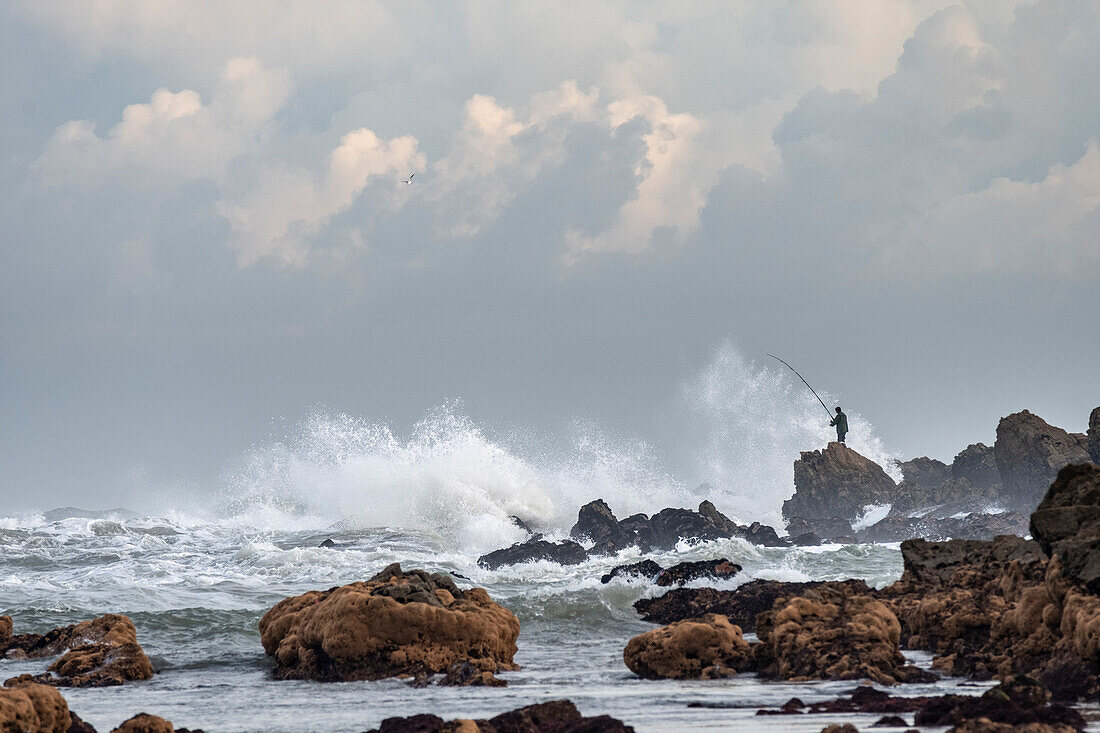 Africa, Morocco, Casablanca. Man fishing amid ocean waves