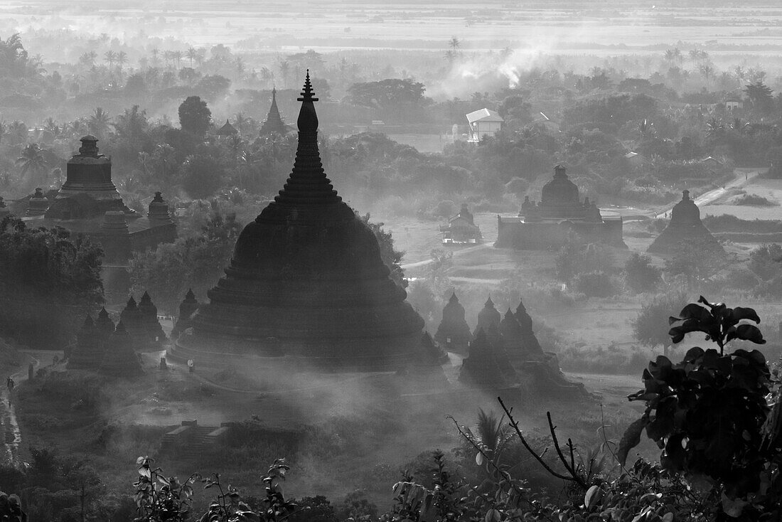 Alte Tempel und Pagoden im Dschungel, die sich aus dem Nebel des Sonnenuntergangs erheben, Mrauk-U, Staat Rakhine, Myanmar