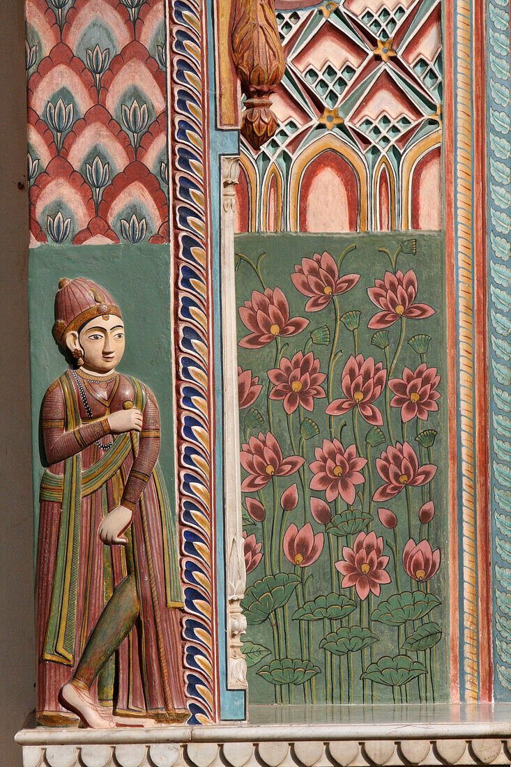 Jaipur, Rajasthan, India. City Palace. Wood carved wall with Lotus flowers, painted decorations, and an India woman