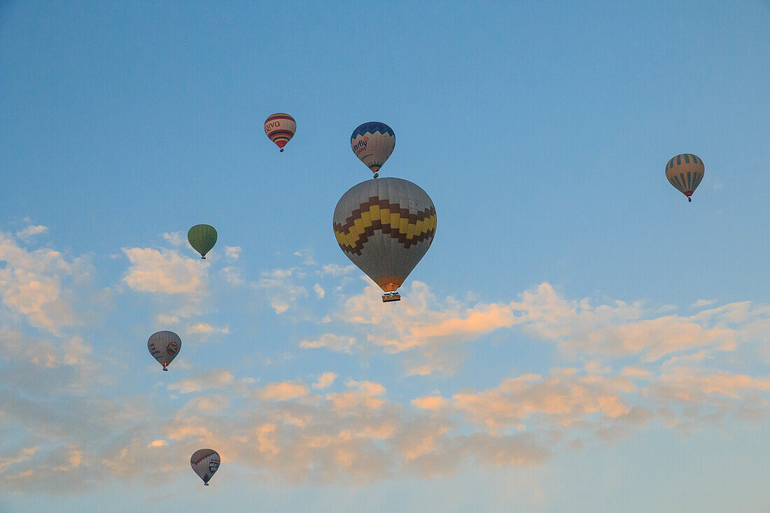 Turkey, Anatolia, Cappadocia, Goreme. Hot air balloons flying above rock formations and field landscapes in the Red Valley, Goreme National Park, UNESCO World Heritage Site.