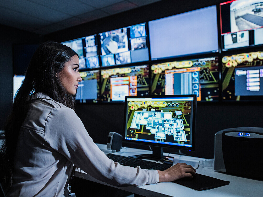 Mixed race security guard watching monitors in control room