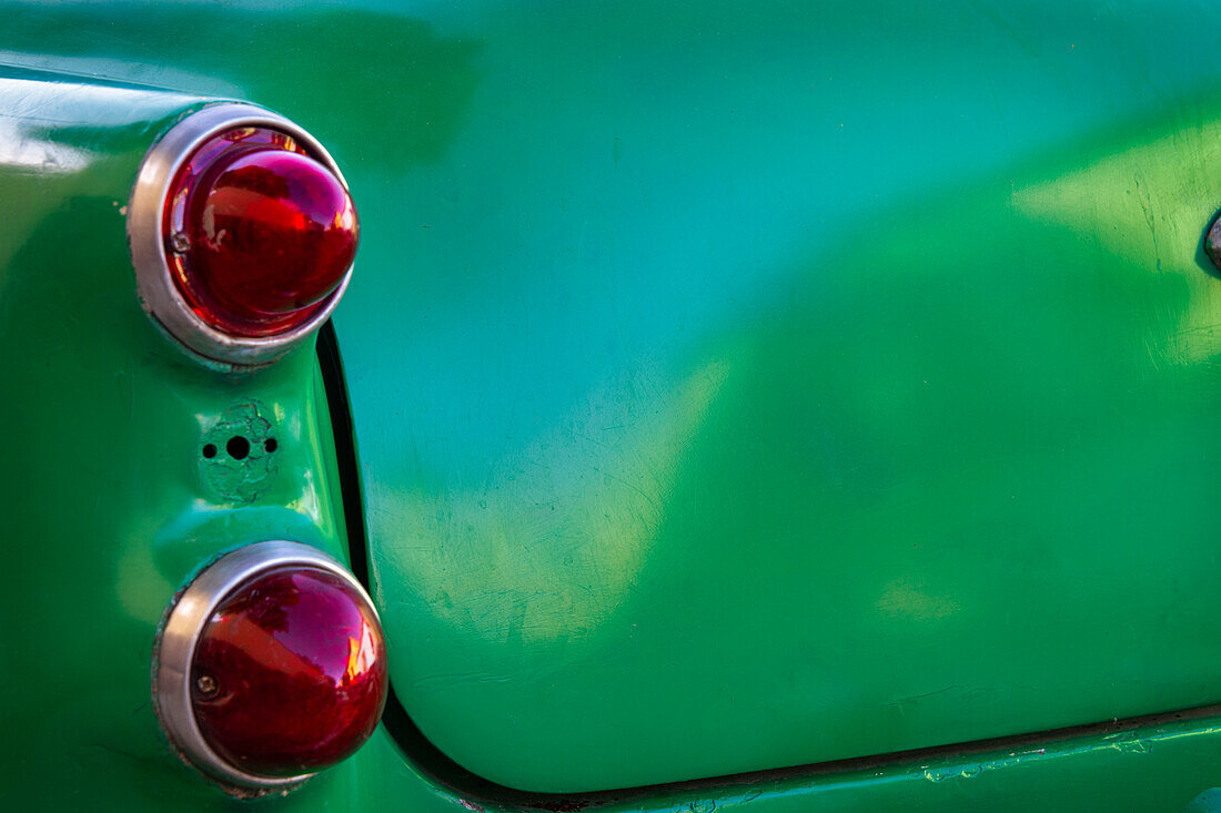 Detail of two red tail lights on classic green car in Trinidad, Cuba