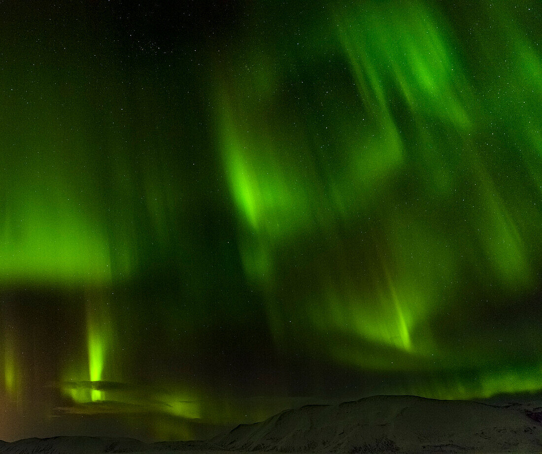 Northern Lights or aurora borealis over the mountains between Thingvellir and Laugarvatn during winter in Iceland.