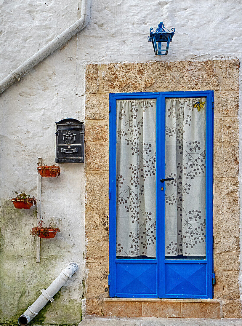 Italien, Apulien, Brindisi, Itria-Tal, Ostuni. Blaue Tür mit Vorhängen in der Altstadt von Ostuni.