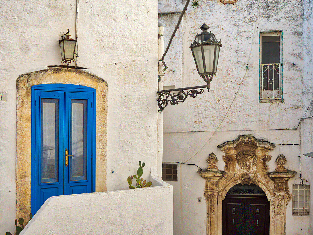 Italien, Apulien, Brindisi, Itria-Tal, Ostuni. Eine blaue Tür und kunstvolle Schnitzereien umgeben ein weiteres Portal.