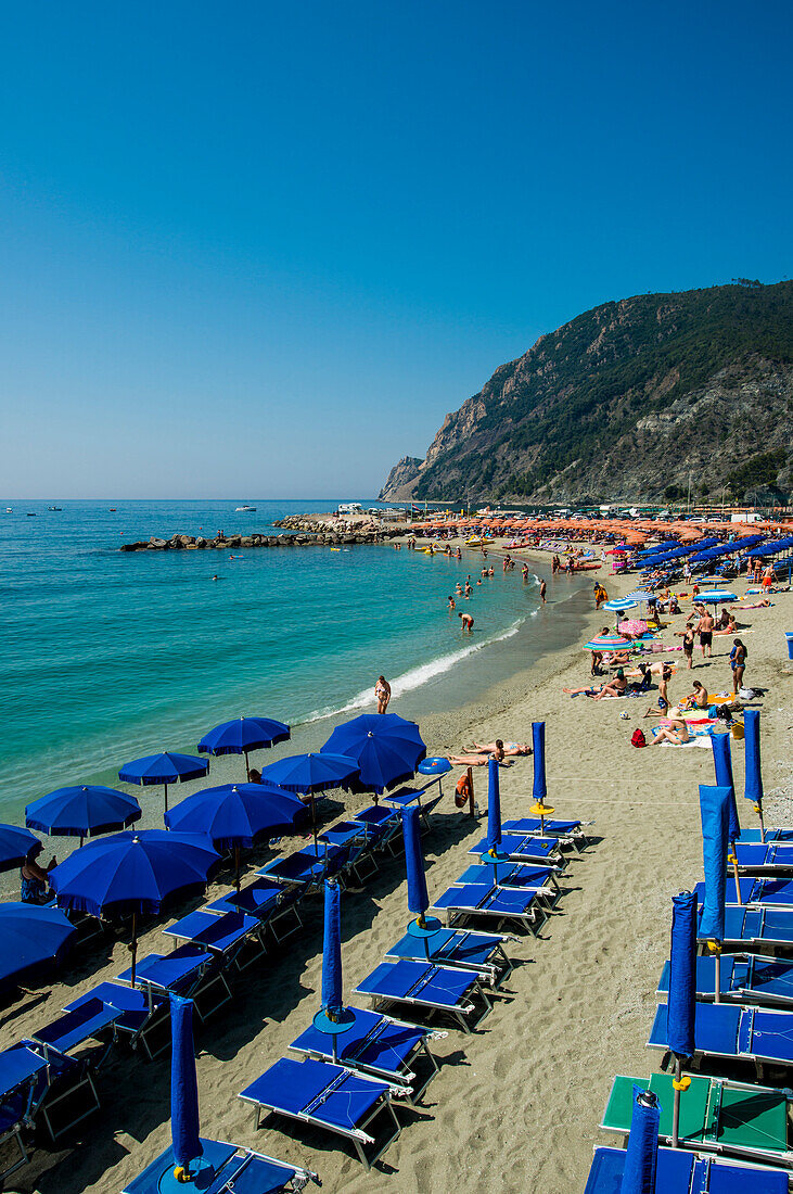 Beach umbrellas lining the beach in Monterosso al Mare, Cinque Terre, Italy.