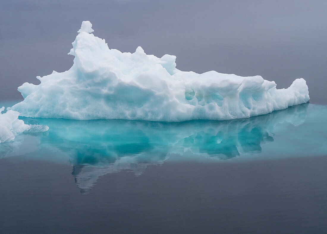 Arktisches Meer, Norwegen, Svalbard. Eisberg spiegelt sich im Meer