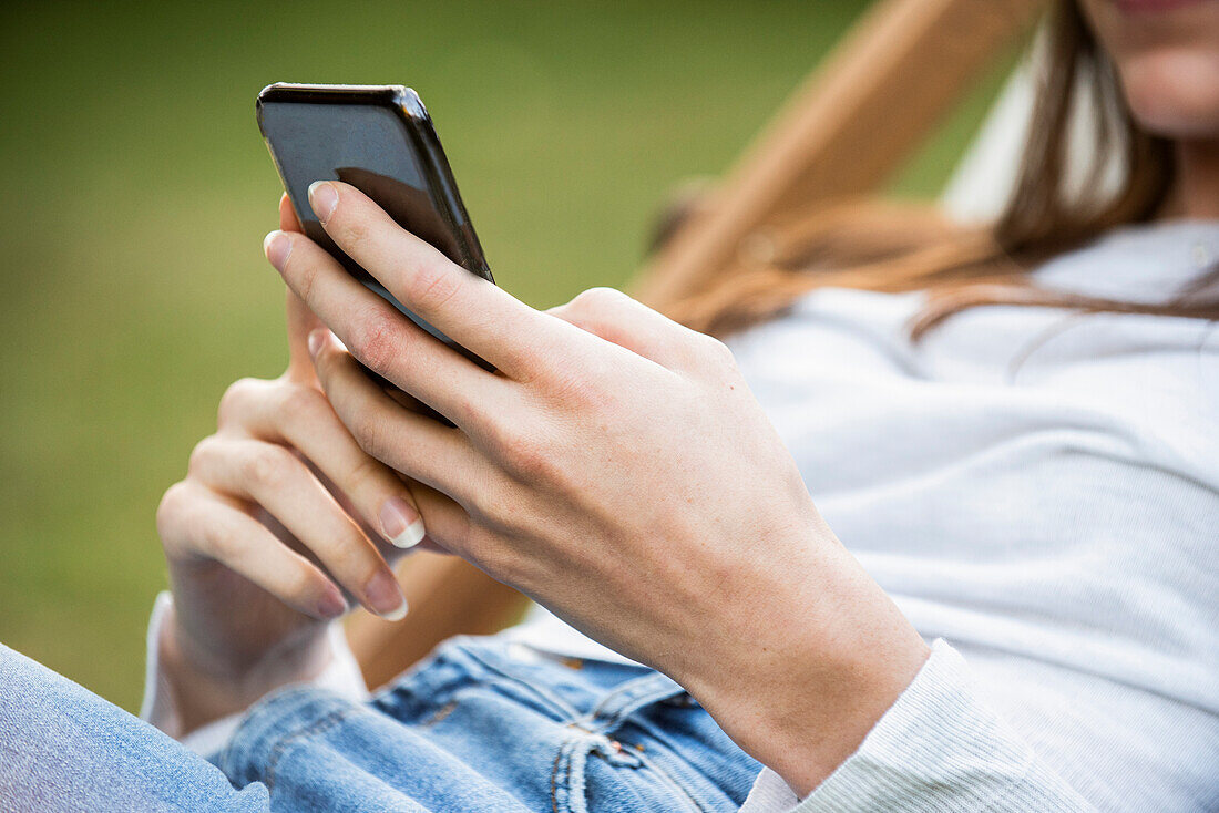 Mid section of young woman using smartphone in park