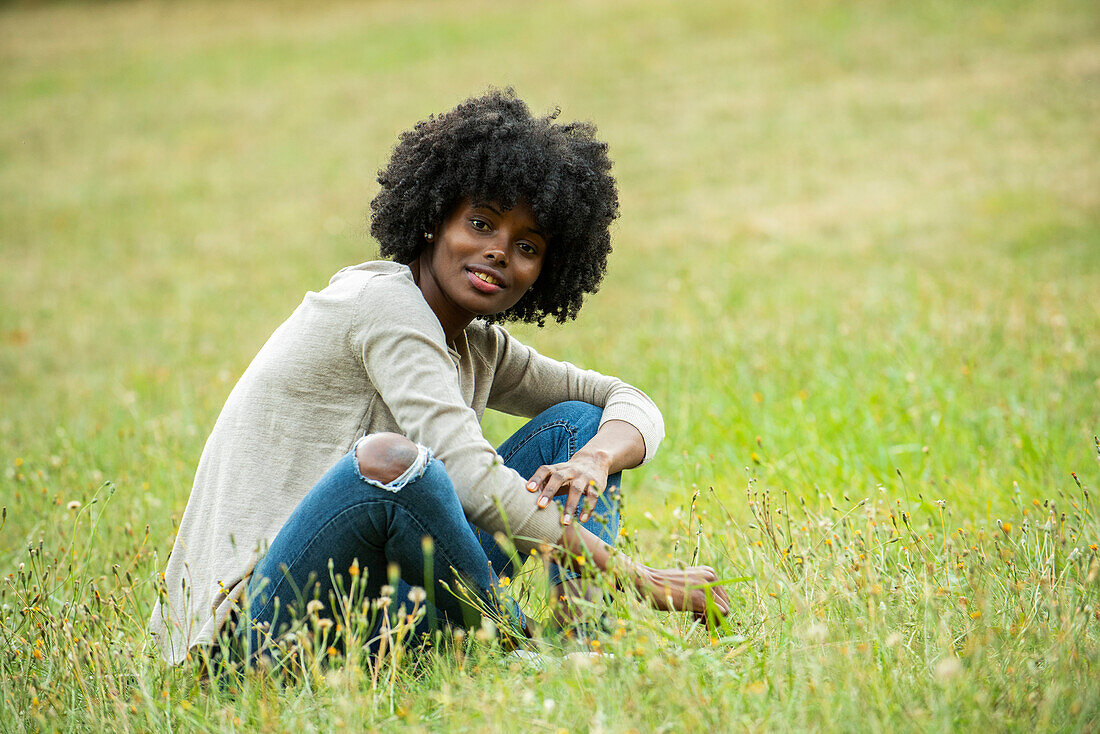 Nachdenkliche junge Frau sitzt im Park
