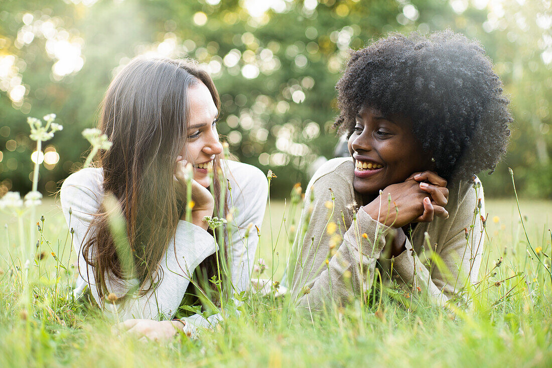 Portrait of smiling young female friends lying in park