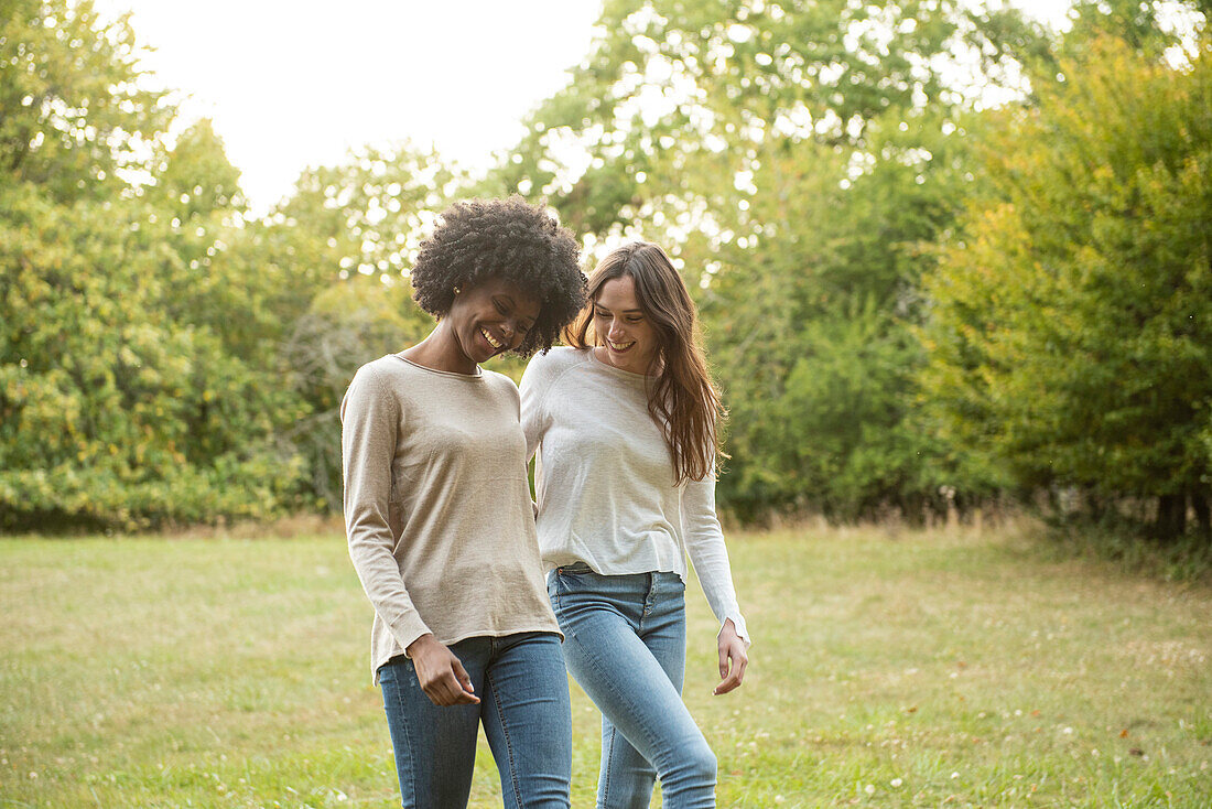 Smiling young female friends walking in park