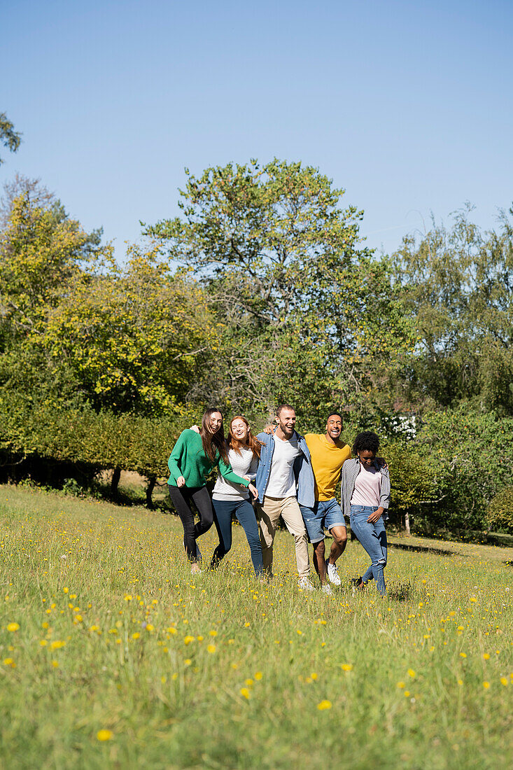 Fröhliche junge Freunde, die Spaß haben, während sie zusammen im Park laufen