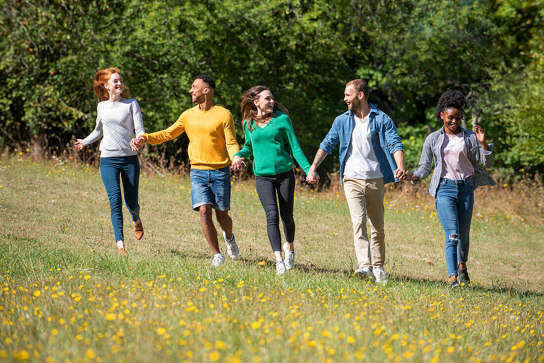 Glückliche junge Freunde, die zusammen in einem öffentlichen Park spazieren gehen