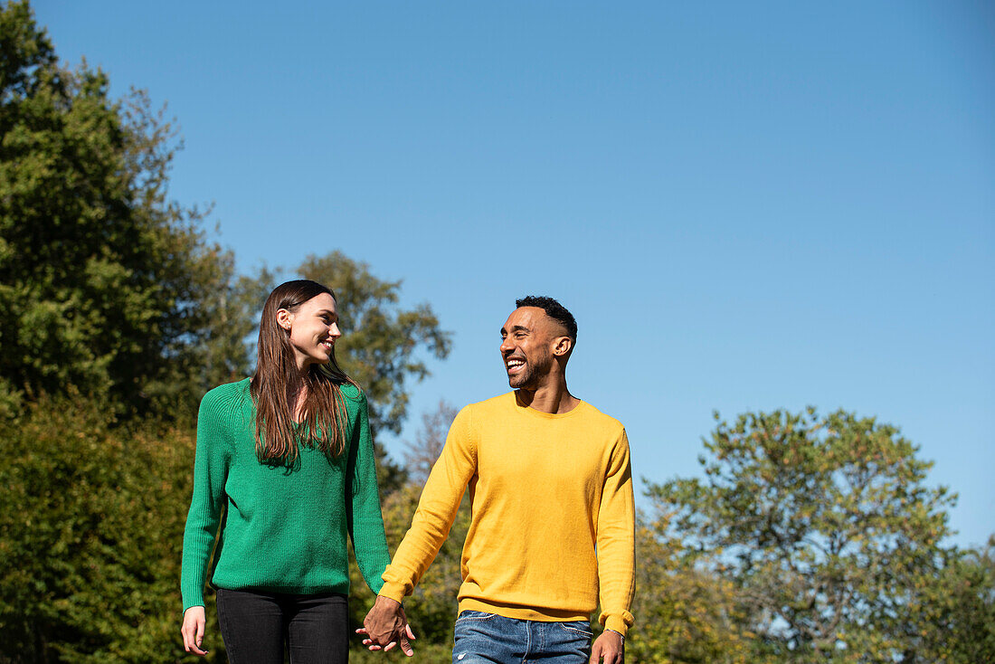 Smiling young couple walking in public park