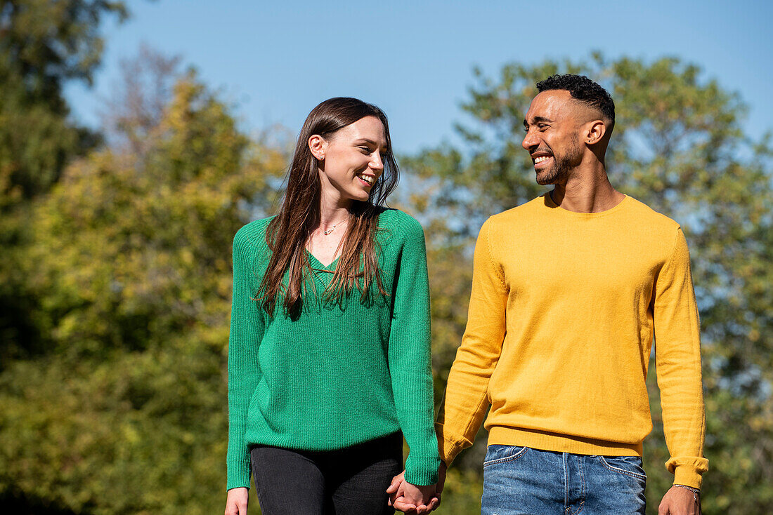 Smiling young couple walking in public park