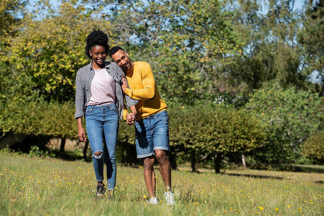 Smiling young couple walking in public park