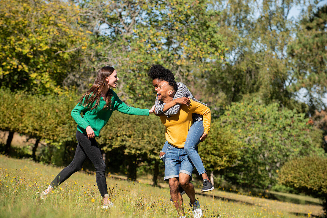 Smiling young friends having fun while walking in public park