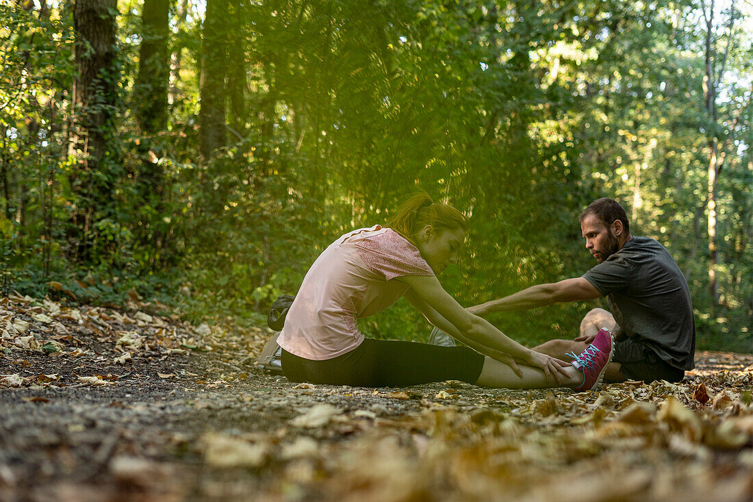 Junges Paar, das auf einem Feldweg im Wald trainiert