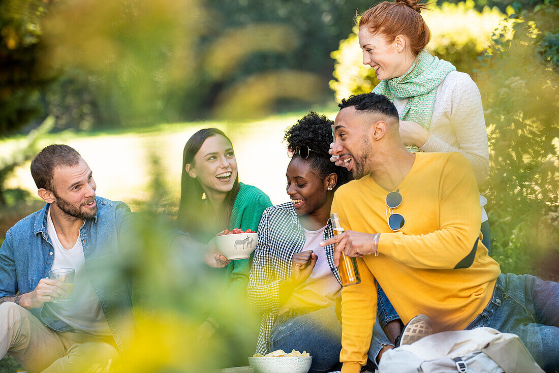 Happy young friends having picnic in public park