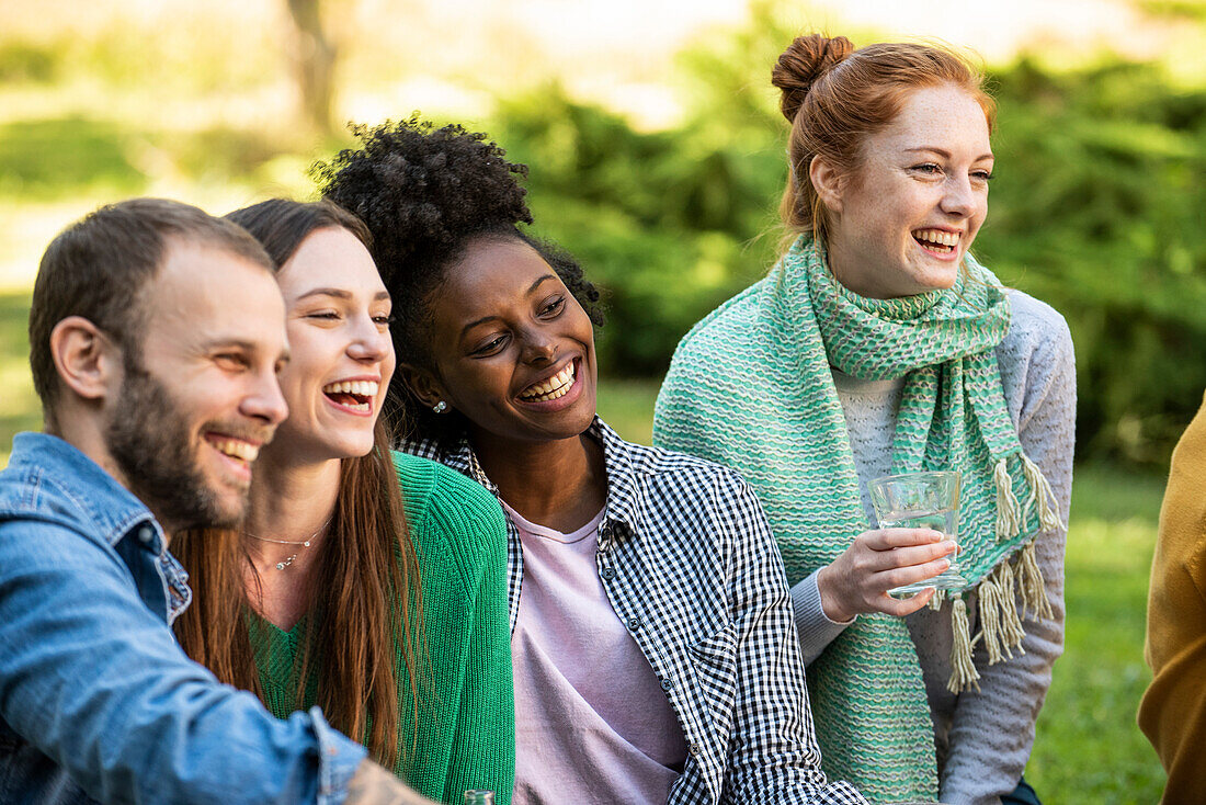 Porträt von lächelnden jungen Freunden beim Picknick in einem öffentlichen Park