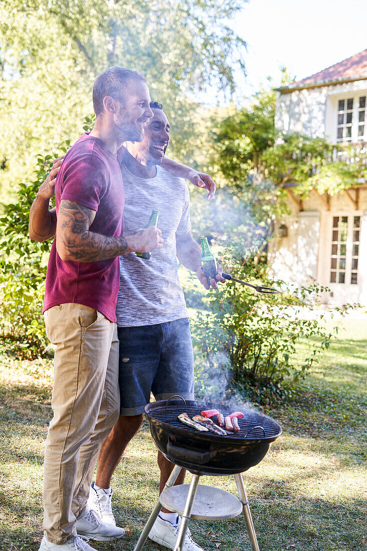 Junge Männer mit Bierflaschen stehen in der Nähe des Grills