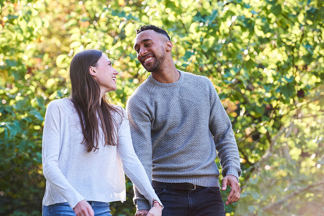 Smiling young couple looking at each other in public park