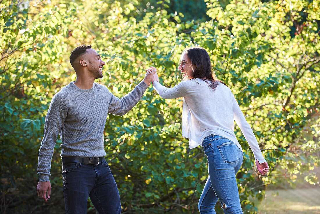 Smiling young couple dancing in public park