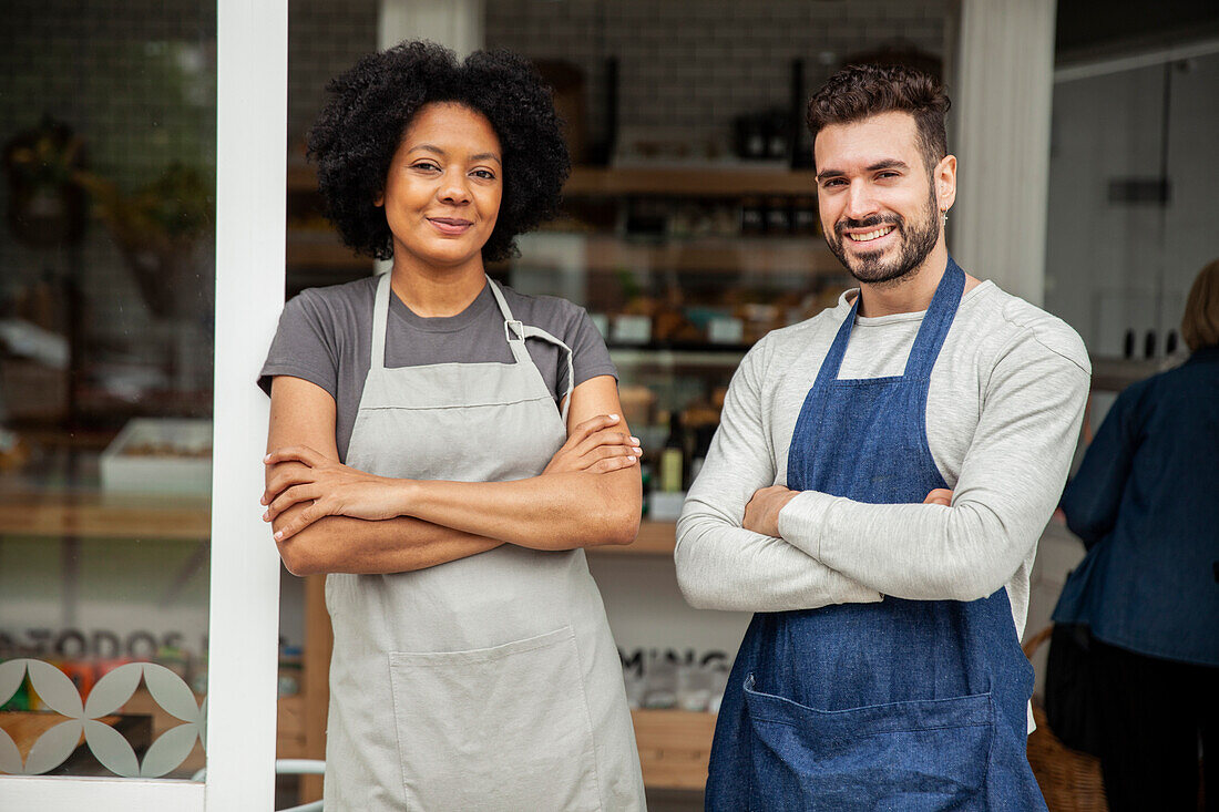 Bäckereibesitzer mit Schürze stehen mit verschränkten Armen