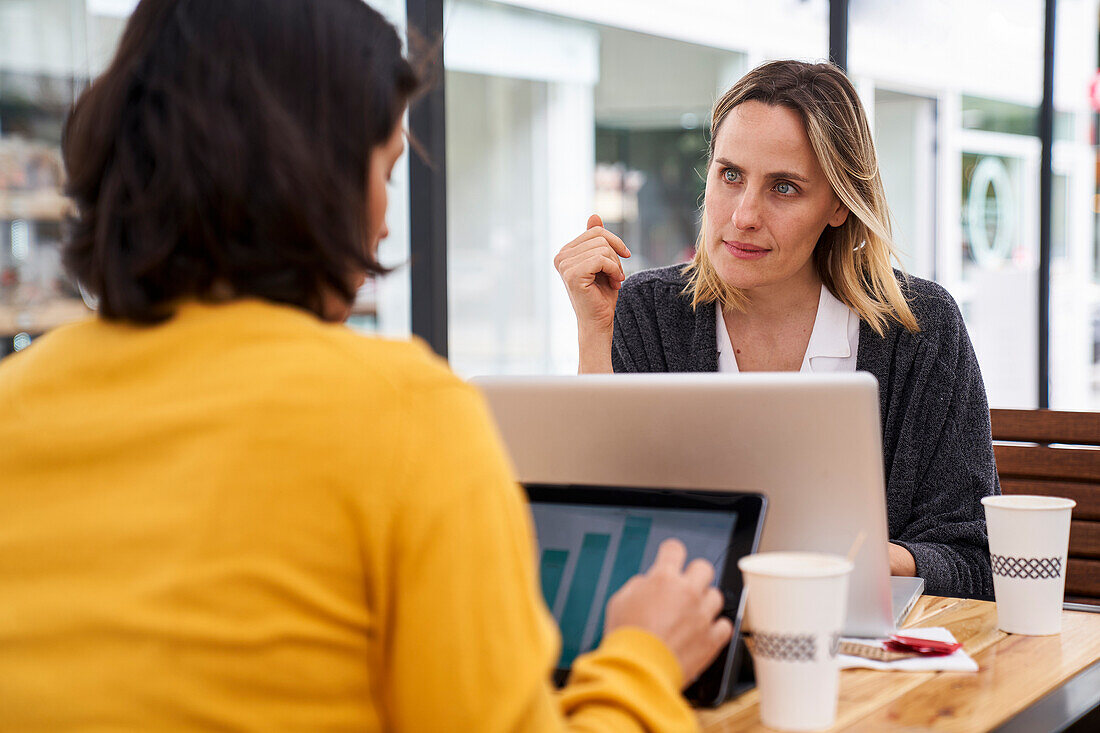 Mid-shot view of female co-workers discussing in outdoors office