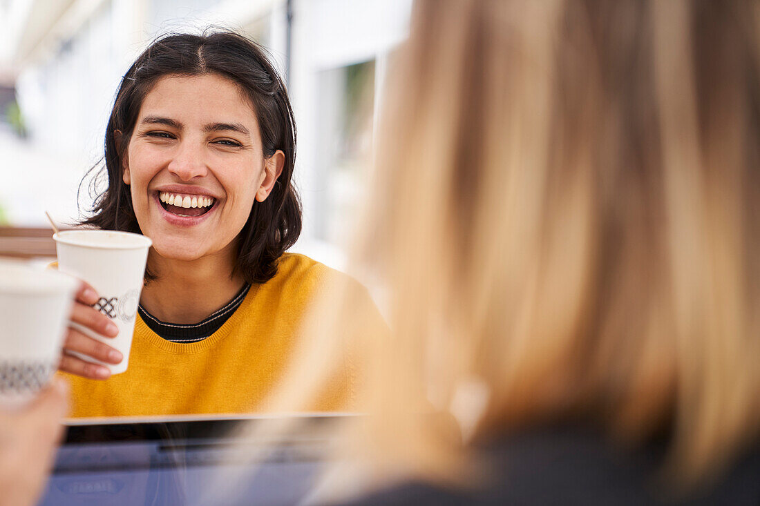 Mid-shot front view of Latin-American businesswoman laughing with her co-worker